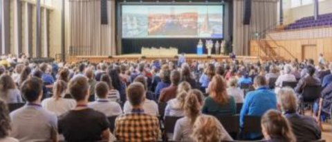 udience attending a gynecology and obstetrics congress, watching a presentation or speaker in a conference hall.